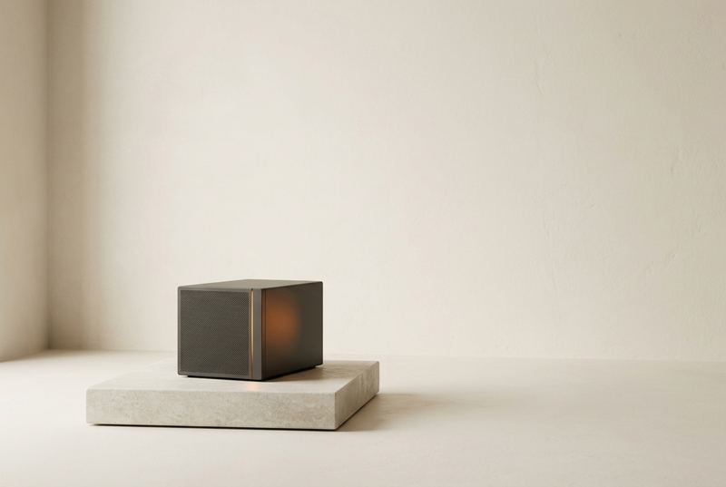 A small, unbranded matte grey server appliance on a stone plinth with a thin orange light along its edge
